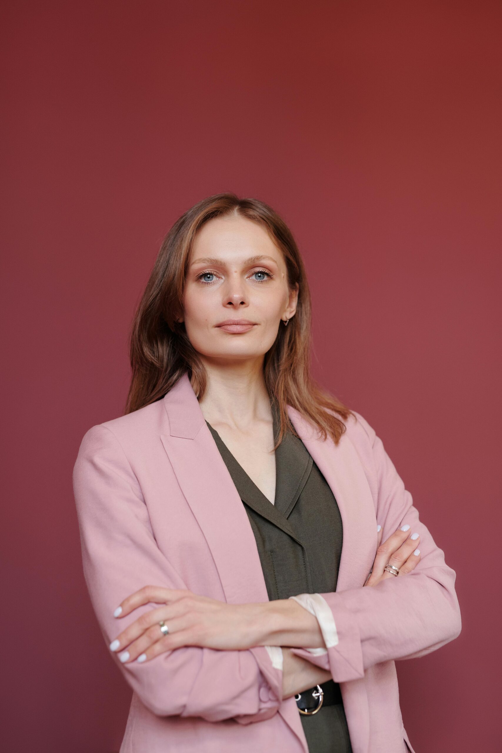 Our Team Elegant businesswoman with arms crossed in studio portrait, showcasing leadership and confidence.